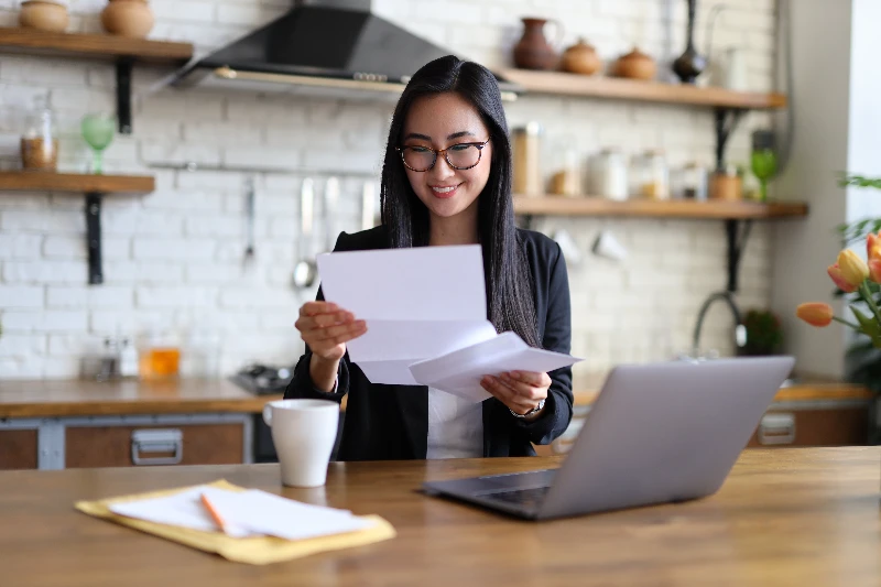 Blog 9 Businesswoman happily reads financial letter at a desk with laptop